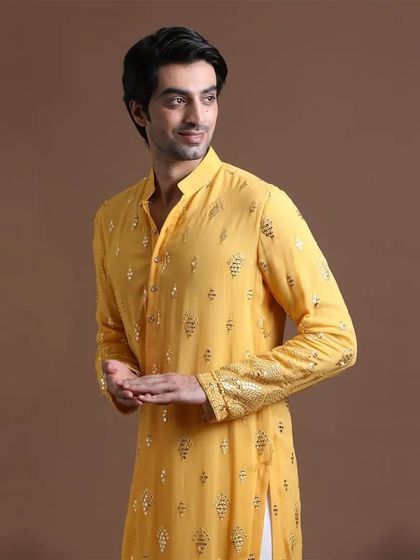 A close-up of a yellow kurta with detailed embroidery on the cuffs and body. This highlights the craftsmanship that goes into each piece, ensuring you look your best.