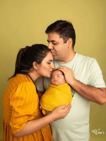 Kisses for the little one. This pose beautifully captures the overwhelming love and affection parents feel, creating a heartwarming and emotional family photograph.
