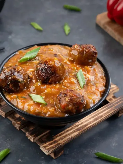 A bowl of vegetable manchurian in a rich gravy, styled with dark, moody tones. This approach is great for creating a cozy and satisfying feel for savory dishes.
