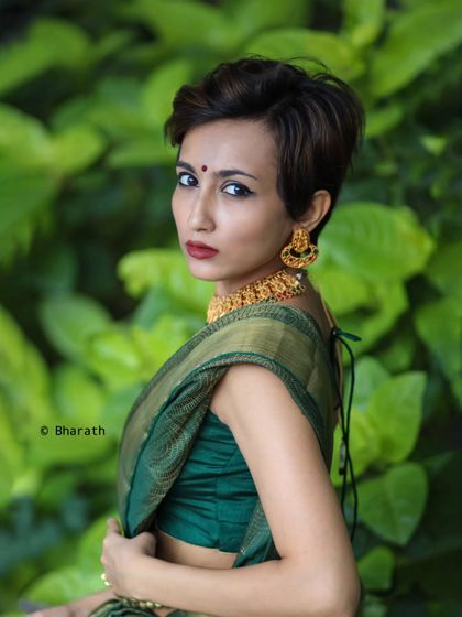A powerful and confident outdoor portrait, showcasing a modern hairstyle with a traditional green saree.