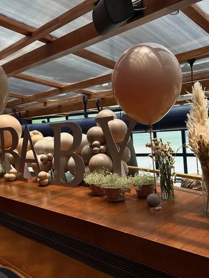 A custom "BABY" sign serves as a beautiful focal point on the bar, surrounded by delicate baby's breath and neutral-toned balloons for a sophisticated touch.