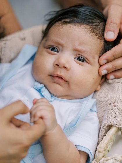A close-up of an alert newborn, held securely in his parents' hands. His direct gaze is captivating and full of wonder.