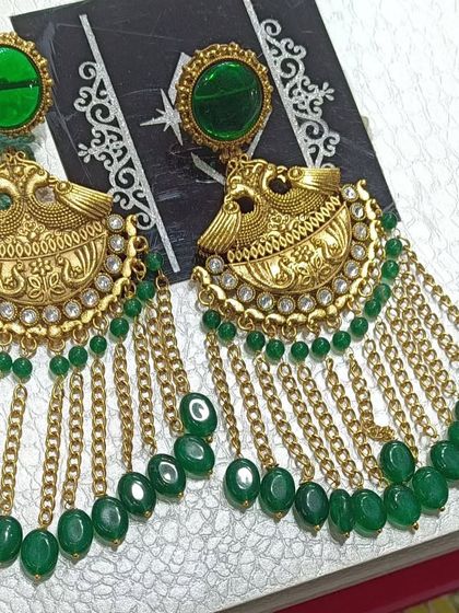A closer look at the peacock motif earrings with green beads and chains. The antique gold finish gives them a very traditional and royal feel.