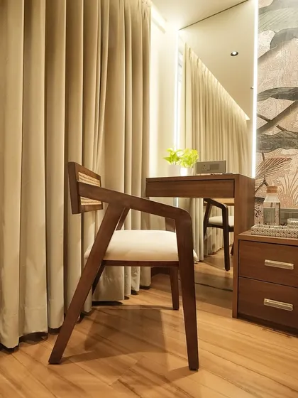 This shot shows the chair as part of a vanity setup, reflected in a large mirror. The combination of natural materials and thoughtful placement creates a functional and beautiful personal space within the bedroom.