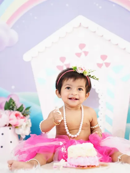 The best part of a cake smash! A happy baby girl in a pink tutu enjoying her first birthday cake, with frosting and pearls everywhere.
