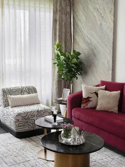 The interplay of textures is key in this design. A plush area rug, a velvet sofa, and a patterned armchair come together to create a living space that is rich in visual and tactile interest.