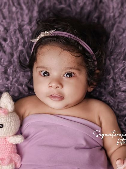 A curious four-month-old baby with her little bunny friend, showing her bright eyes and sweet expression.