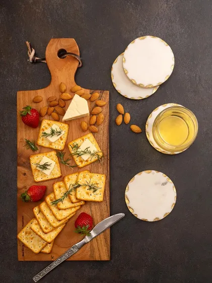 A dark and moody flat lay of a cheese board, styled with crackers, strawberries, and almonds. This top-down shot is dramatic and highlights the texture of both the food and the wooden board.