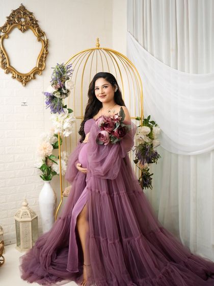 A lovely portrait of the expecting mother holding a bouquet. The soft colors of the flowers perfectly complement her beautiful purple dress.