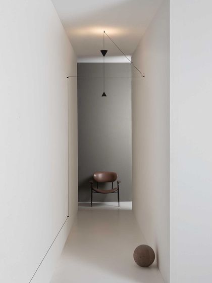 A single Filomena pendant is guided by a series of wall and ceiling mounts to illuminate a narrow hallway, demonstrating its problem-solving capabilities.