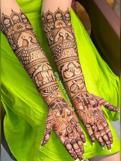 A grand design for a grand day. This full-arm bridal henna includes everything from couple portraits and wedding rings to peacocks and elephants, telling a complete story.