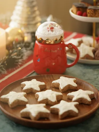 Star-shaped Christmas cookies on a wooden plate, next to a festive Santa mug, creating a cozy and whimsical holiday mood.