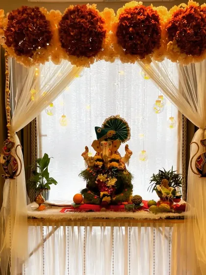 Creating a serene and beautiful space for Ganpati Bappa. This home mandap decoration uses a backdrop of sheer curtains and marigold floral arrangements, with delicate lighting to create a divine atmosphere for the festival.
