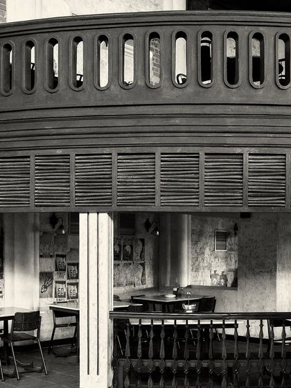 A view from the upper balcony looking down into a seating area with louvered wooden panels.