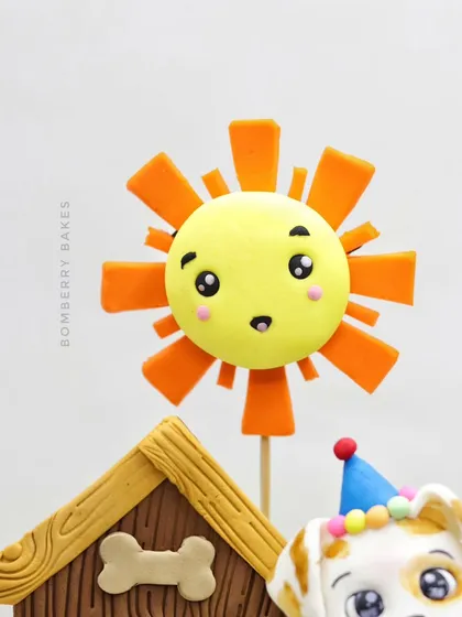 A detailed shot of the cheerful, sculpted sun topper from the gravity-defying cake.