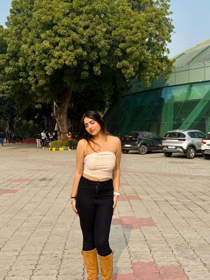 A simple yet stylish outfit with a beige tube top, black jeans, and brown boots. This is a perfect example of a transitional, fall-inspired look.