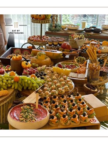 A low-angle shot of a magnificent grazing table, emphasizing its abundance and the variety of bites available, from canapés to dips and fresh fruit.