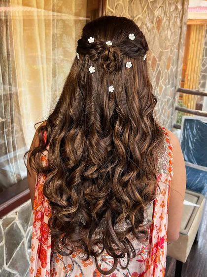 A detailed shot of the Mehendi hairstyle, with soft curls and delicate floral accessories.