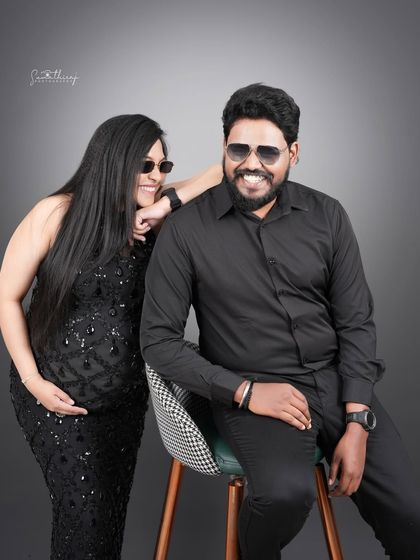 Another fun and candid shot of a couple in matching black outfits and sunglasses. Their smiles and relaxed poses capture their joyful and modern approach to parenthood.