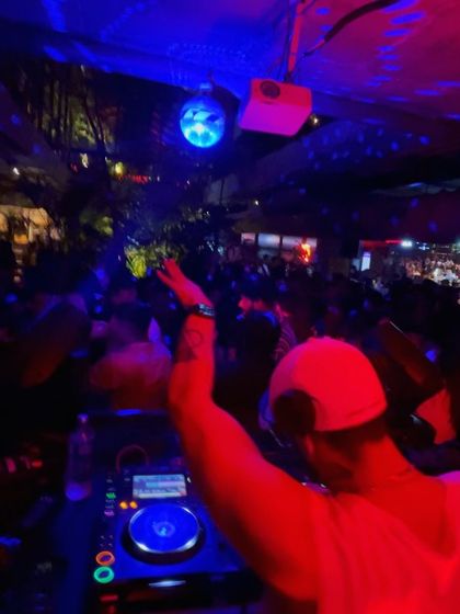 From behind the decks, with my arm in the air, leading the crowd. The energy is a two-way street.