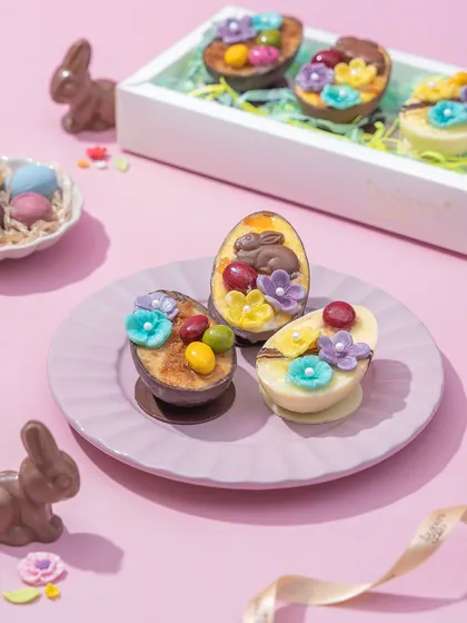 A box of my unique cheesecake eggs, featuring a creamy cheesecake filling inside a chocolate egg shell, topped with edible flowers and mini bunnies. It's a creative and delicious twist on the classic Easter egg.