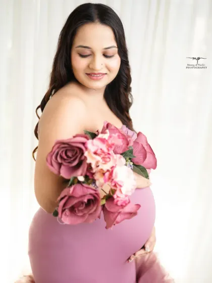 A soft and delicate close-up. Holding a bouquet, the mother-to-be has a serene expression, creating a portrait of pure maternal grace.