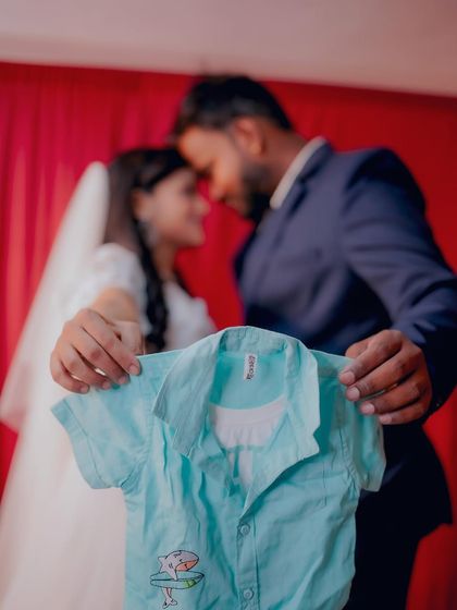 A creative announcement shot where the couple holds up a tiny baby shirt. This is a popular way to add a personal touch to your maternity photos.