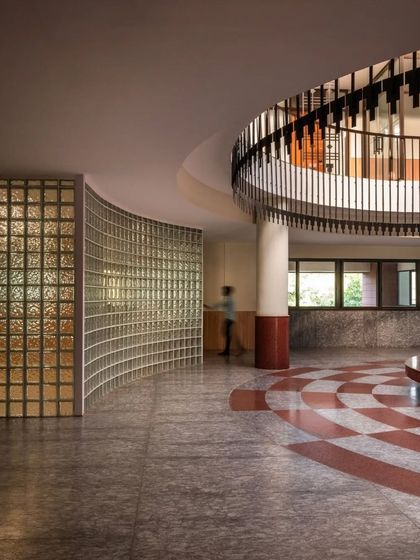 The main lobby features a curved glass block wall and a circular atrium, creating a sense of fluid movement and transparency.