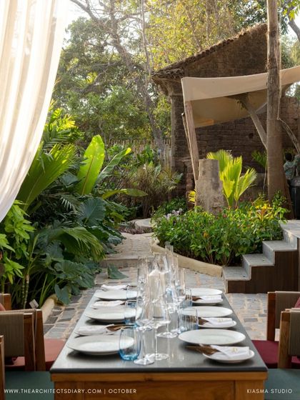 A long dining table set for a meal at Sanctuary Bar, surrounded by lush greenery. The design focuses on creating intimate and beautiful spaces for gathering within the larger landscape.