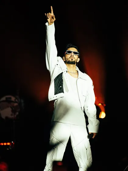 Anirudh Ravichander strikes a commanding pose during his Hukum Tour in Bangalore. Dressed in all white, he points to the sky under a single spotlight, a moment of pure star power.