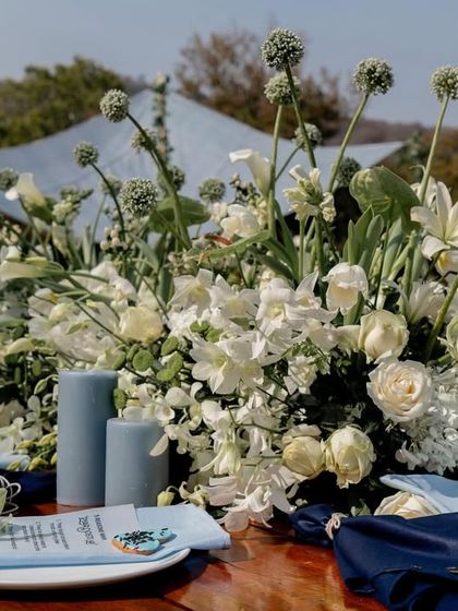 A beautiful tablescape from the modern Haldi, featuring a runner of white florals and dusty blue candles, showing a fresh and unique color palette.
