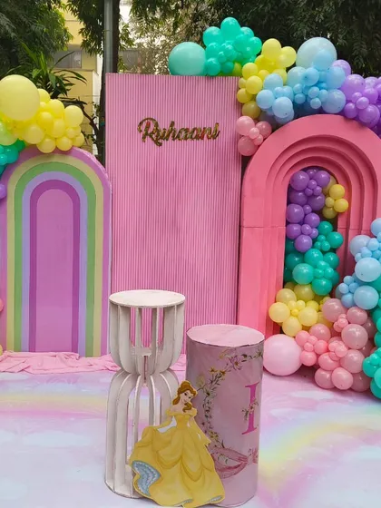 A modern and colorful princess party backdrop with pastel rainbow arches and organic balloon garlands.