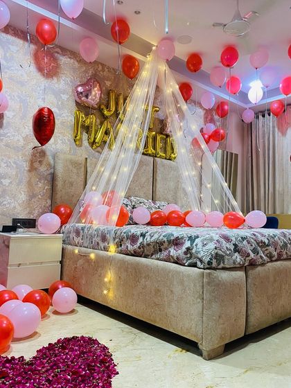 A close-up of the bed area, showing the gentle drape of the lit canopy and the mix of pink and red balloons.