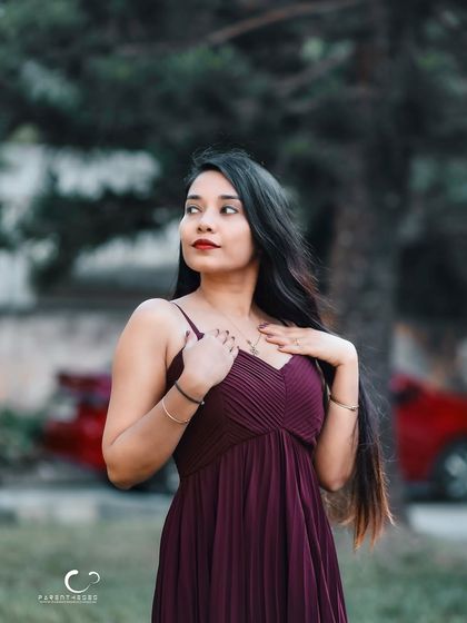 A soft and gentle pose with hands to her chest. Her expression is serene, and the natural background adds a sense of calm.