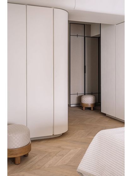 The master bedroom's walk-in closet area features curved, seamless wardrobes and warm herringbone flooring, creating a luxurious and functional private space.