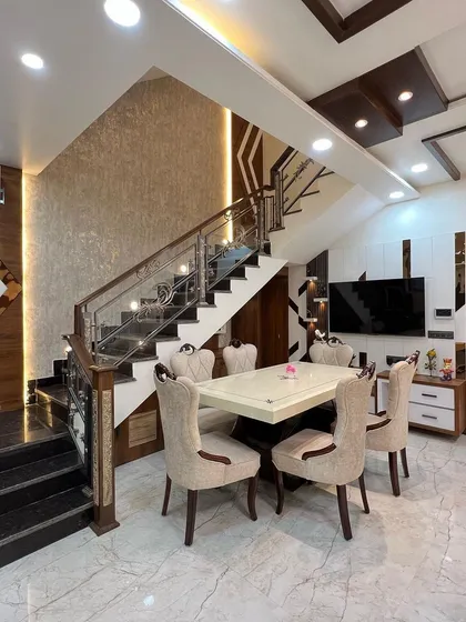 A detailed shot of the dining and staircase area. The combination of dark wood, stainless steel railings, and intricate wall textures creates a rich and luxurious feel.