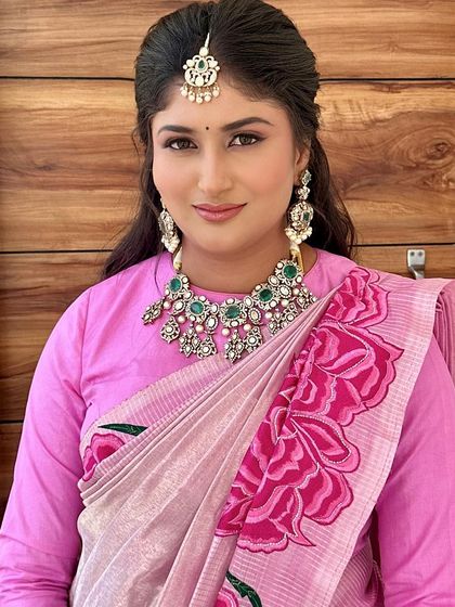 A smiling portrait showcasing a modern look with a full-sleeve blouse and half-up hairstyle.