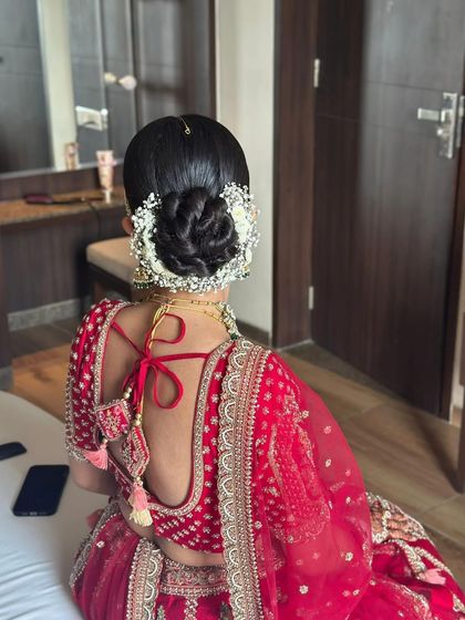 A clean and classic twisted bun, perfectly framed by a traditional white gajra. This is an ideal hairstyle for the main wedding ceremony.