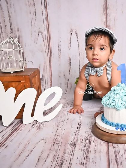 A classic pose from a first birthday cake smash. This little boy looks on with curiosity before diving into his beautifully decorated blue cake.