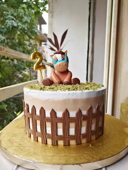 One of the cutest cakes I've ever made. This design features a little fondant pony sitting in a field, surrounded by a chocolate fence. It was for a second birthday party.