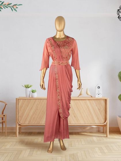 This hand-stitched georgette drape dress in a soft peach hue is both elegant and modern. The delicate embroidery and matching belt create a flattering silhouette, perfect for any celebration.