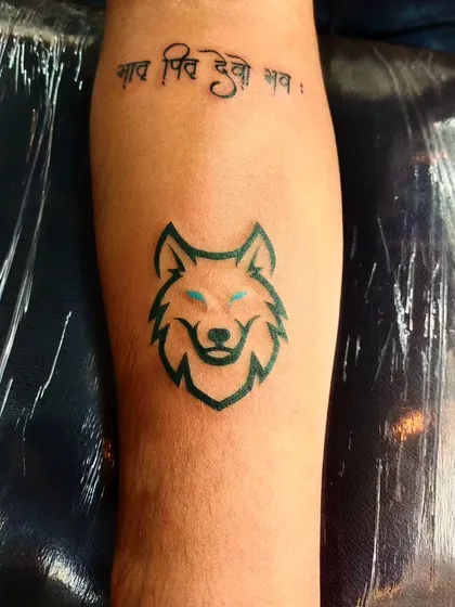 A stylized wolf head tattoo with glowing blue eyes. This design is a modern and graphic representation of loyalty and instinct.