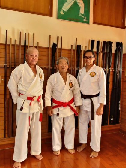 A student stands with two highly respected red-belted masters at the Honbu Dojo in Okinawa.