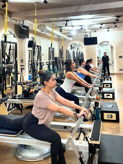 A full class of clients engaged in a rowing series on the Reformer. This exercise is fantastic for strengthening the back, shoulders, and core muscles.