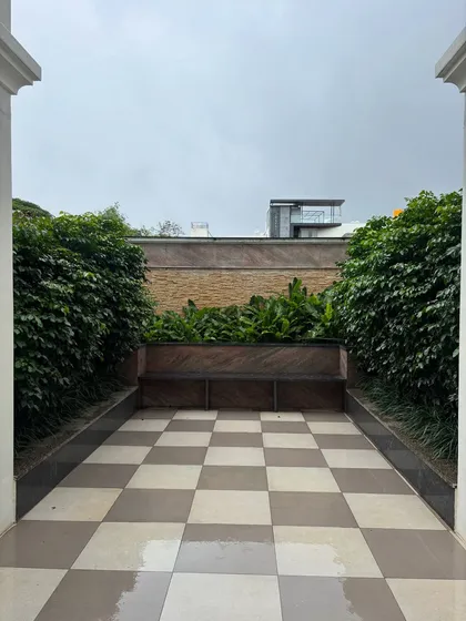A simple, symmetrical view of a residential courtyard. The lush green walls of foliage create a private, enclosed space that feels like a secret garden.