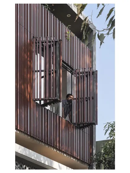 A resident looks out from the operable window on the second floor, a feature that allows the home to open up and breathe.