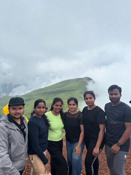A group of trekkers posing together on the trail, with the misty Netravathi hills behind them.