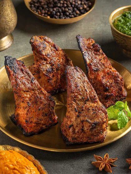 Mutton Burra, showcasing the perfectly grilled and spiced meat. The simple plating on a brass dish for The Mughal House lets the food stand out.