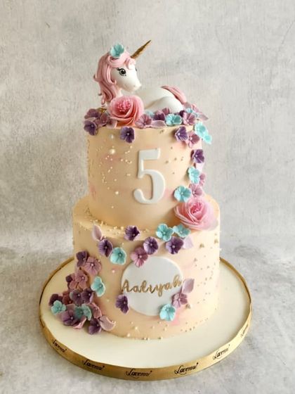 A magical unicorn cake for Aaliyah's 5th birthday. This two-tiered cake is decorated with a cascade of handmade sugar flowers and a beautiful unicorn figurine on top.