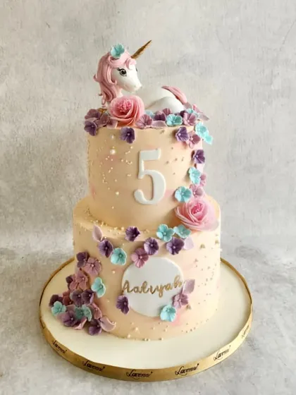 A magical unicorn cake for Aaliyah's 5th birthday. This two-tiered cake is decorated with a cascade of handmade sugar flowers and a beautiful unicorn figurine on top.